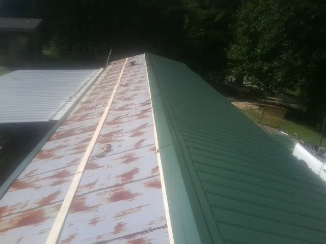 Old rusted panels beside newly installed green metal roofing — Wind Damage Roof Repair by Roofing Brothers in Island Lake
