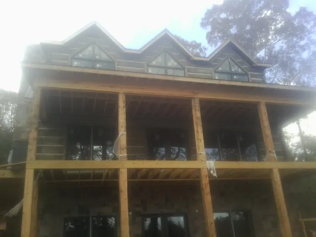 Dormers and porch framing on a large log home under construction — Roof Coating work by our crew in Island Lake