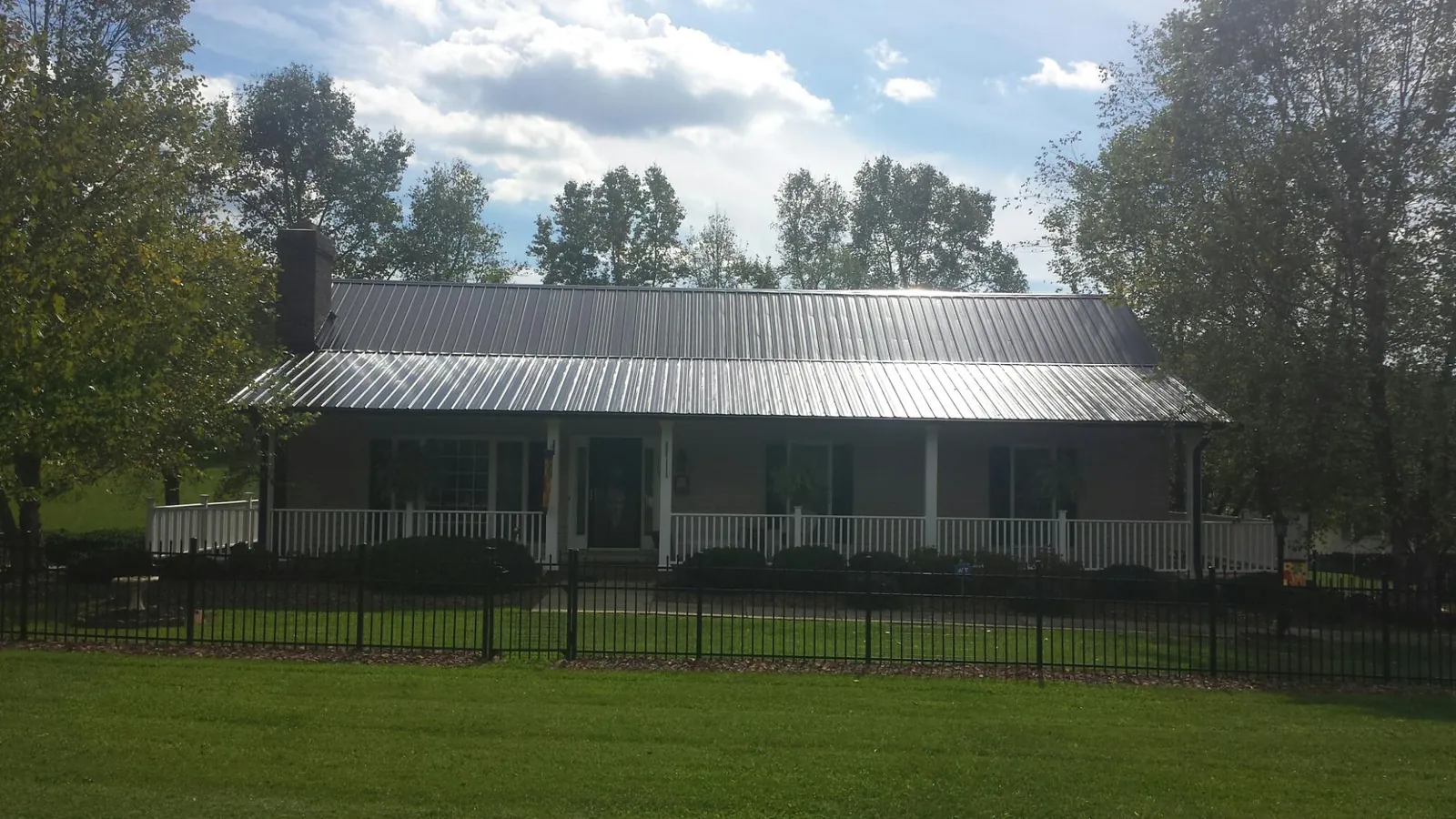 Gray metal roof on a brick ranch with a full width front porch — Gutter Guard Installation work by our crew in Island Lake