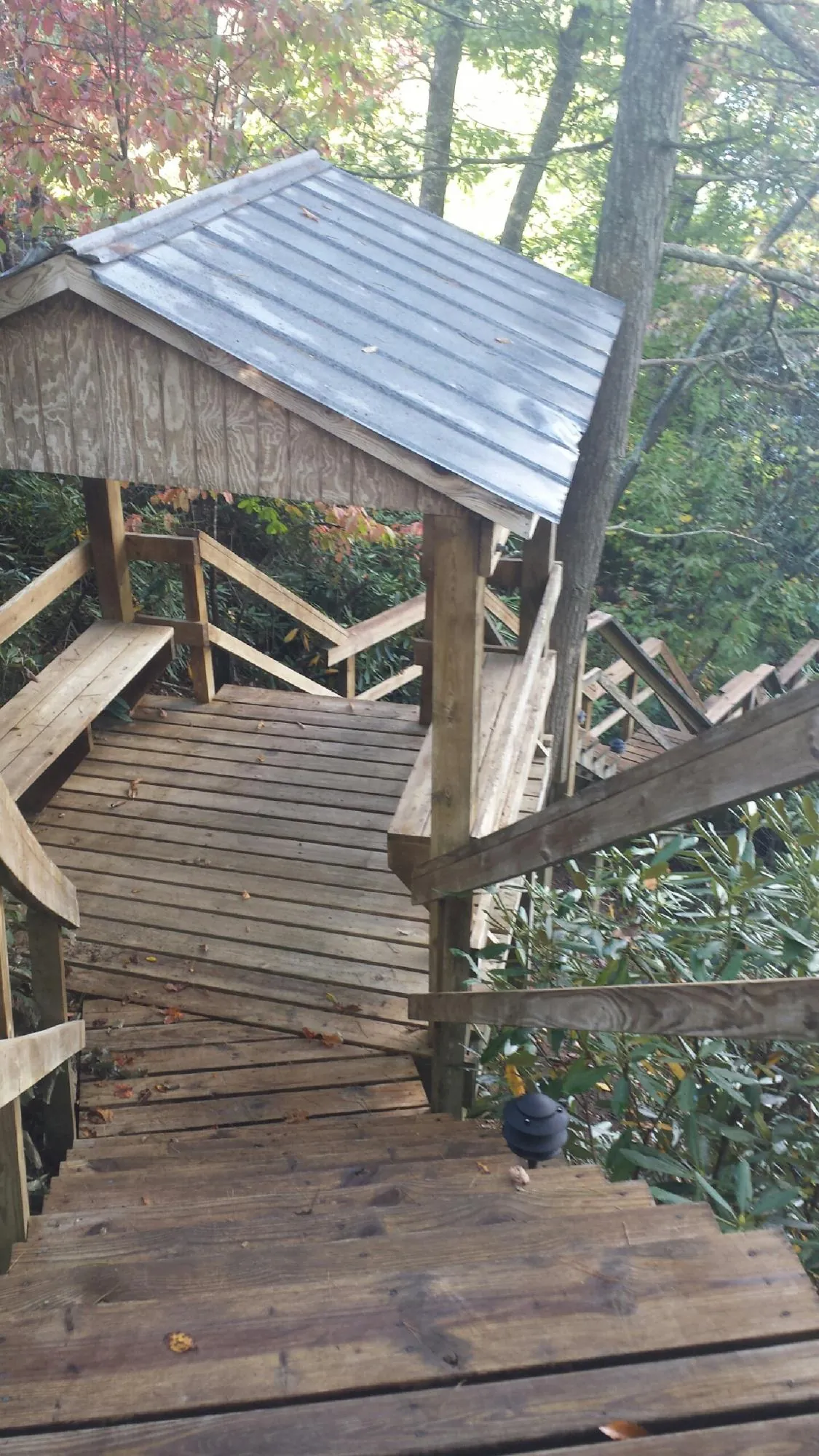Metal roofed shelter over wooden steps on a wooded walkway — Skylight Repair & Installation work by our crew in Island Lake