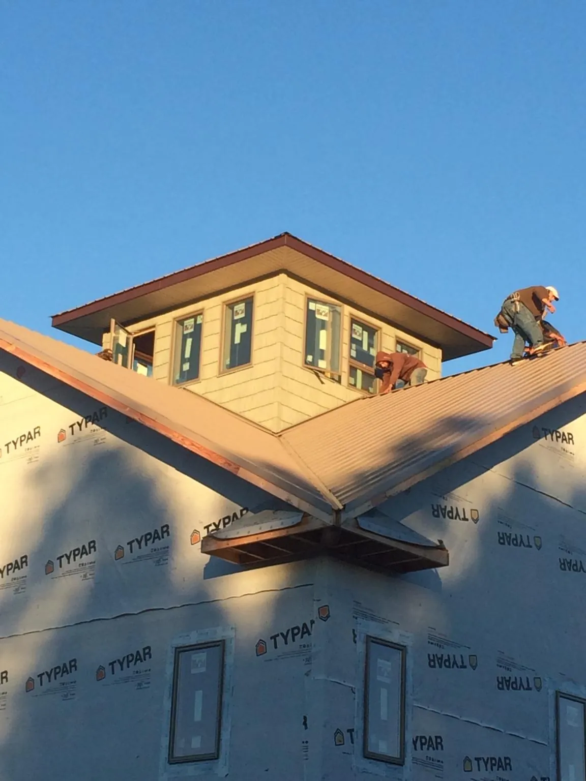 Roofers working around a rooftop cupola on a new metal roof at sunset — Roof Waterproofing in Island Lake by Roofing Brothers